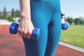 Topic: sports and health. Girl runner stands with dumbbells at the running stadium Royalty Free Stock Photo