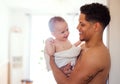 Father and small toddler son wrapped in towel in a bathroom indoors at home.