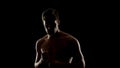 Topless free fighter preparing for sparing, dark background, shadow fight