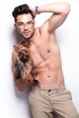 Topless young man holds puppy while posing