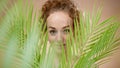 Topless young woman in a studio with palm leaves looking at camera, beauty concept. Royalty Free Stock Photo