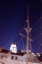 Topmast and cables of an old ship from the time of the discoveries against a clear bell tower at night. Royalty Free Stock Photo