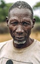 TOPOSA TRIBE, SOUTH SUDAN - MARCH 12, 2020: Elderly male in dirty t shirt and with traditional scars on face looking at