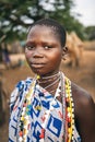 TOPOSA TRIBE, SOUTH SUDAN - MARCH 12, 2020: Teen girl in ornamental garment and with colorful accessories looking at camera on