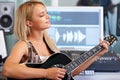 Topping the charts, one riff at a time. A beautiful blonde woman playing guitar in a recording studio. Royalty Free Stock Photo