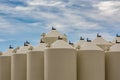 Tops of grain bins against cloudy sky