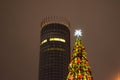 The tops of a skyscraper and a Christmas tree against the background of the night sky Royalty Free Stock Photo