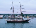 Topsail schooner sitting in a harbor with the children sitting on the bow