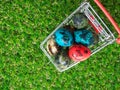 Topview of colourful of multi easter eggs in red shopping cart on green grass