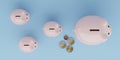 Topview of piggy bank family on blue background with some coins, concept image for saving money Royalty Free Stock Photo