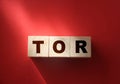 TOR concept on wooden beige cubes on a red background