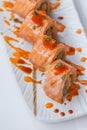 Torched Salmon Maki Sushi with Shrimp Tempura, Avocado and Cheese inside. Topping with Sauce, Ebiko Shrimp Egg and Scallion Royalty Free Stock Photo