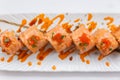 Torched Salmon Maki Sushi with Shrimp Tempura, Avocado and Cheese inside. Topping with Sauce, Ebiko Shrimp Egg and Scallion Royalty Free Stock Photo