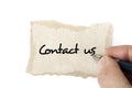 Torn blank cardboard paper with the hand and the pen. Contact us. Royalty Free Stock Photo