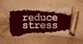 Torn brown paper on dark red surface with Reduce Stress words