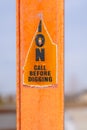 A torn Caution sign on a bright orange post against a blurry background