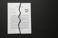 Torn divorce decree with rings on dark background Royalty Free Stock Photo
