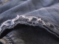 Torn edges of a blue jeans background. Old ripped worn faded jeans background. Distressed grunge denim. Macro.