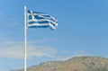Torn greek flag on flag-post against blue sky