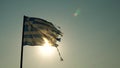 Torn Greek flag waving backlit by summer beach Royalty Free Stock Photo