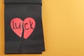 Torn heart and word LUCK written in notebook on orange background. Space for text Royalty Free Stock Photo