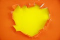 Torn hole and ripped of orange paper with space for text with yellow background Royalty Free Stock Photo