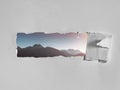 Torn hole in the white paper with a picturesque view of mountains. Creative concept of seeing the world, traveling, open your mind Royalty Free Stock Photo