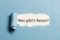 Torn paper revealing the German phrase for `what`s new?` Royalty Free Stock Photo