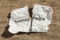 Torn paper written homophobia over wood table. Concept of old an