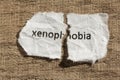 Torn paper written xenophobia over wood table. Concept of old an Royalty Free Stock Photo