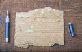 Torn piece of old paper for message or word of wisdom with pen on brown wood Royalty Free Stock Photo