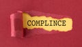 A torn piece of paper with the word Compliance written in black on a red background. Royalty Free Stock Photo