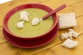 Torn pieces of bread on green pea and ham soup in a red bowl Royalty Free Stock Photo