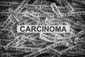 Torn pieces of paper with the words Carcinoma and cancer