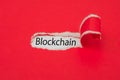 Torn red paper revealing the word blockchain . Business concept