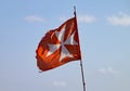 A torn and tattered Maltese Cross flag flies on a fishing boat in Marsaxlokk in Malta Royalty Free Stock Photo