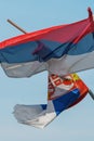 Torn and weathered flag of Serbia on a post waving in wind