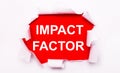 Torn white paper lies on a red background. On red, the text is white IMPACT FACTOR Royalty Free Stock Photo
