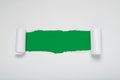 Torn white paper revealing a green background. Royalty Free Stock Photo