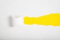 Torn white paper revealing yellow background. Royalty Free Stock Photo