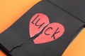 Torn word LUCK with heart written in notebook on orange background Royalty Free Stock Photo