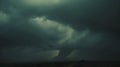 A tornado forming in the distance its dark funnel cloud contrasting against a bleak and stormy sky