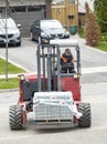 Toronto, Canada - April 28, 2020: Workman Driving a Red Forklift to Move a Pile of Concrete Patio Stones on a Suburban Street 1