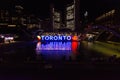 Toronto sign lit up at night, on Nathan Phillips Square is seen with Toronto City Hall in background Royalty Free Stock Photo