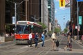 TORONTO, CANADA - 06 27 2016: City dwellers crossing the street in front of an old streetcar on King at Younge st