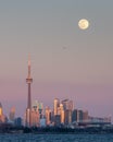 Beautiful soft pink colors at dusk with the full moon rising over the Toronto skyline and CN Tower