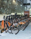 Tangerine bike share docking station at night during a snow storm Royalty Free Stock Photo