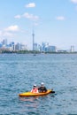 Toronto, Canada - June 28, 2020 : People enjoying the water in a boat on the lake, with the Toronto skyline in the background.