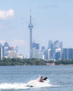 Toronto, Canada - June 28, 2020 : People enjoying the water in a boat on the lake, with the Toronto skyline in the background.