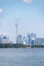 Toronto, Canada - June 28, 2020 : Women enjoying the water paddle boarding across the lake, with the Toronto skyline in the back